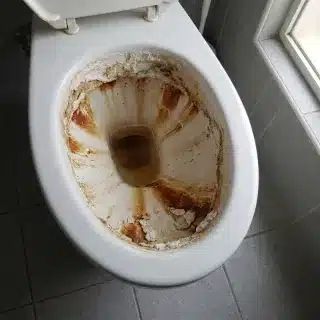 Vorher: Toilette mit braunen Ablagerungen und Kalkkruste unter dem Rand
