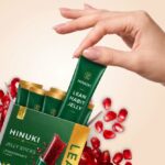 Hinuki Erfahrungen: Hand hĂ€lt die Hinuki Lean Habit Jelly Box mit grĂŒnen Gelee-Sticks und GranatĂ€pfeln